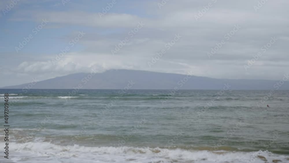 Static view over sea waves crashing on sandy beach in the cloudy evening with the view of mountain silhouette. Static view over sea waves crashing on sandy beach in the cloudy evening with the view of mountain silhouette.