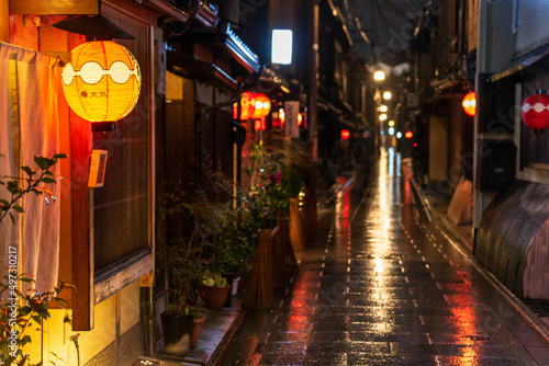 Red lantern illuminates entryway on dark Japanese street after rain