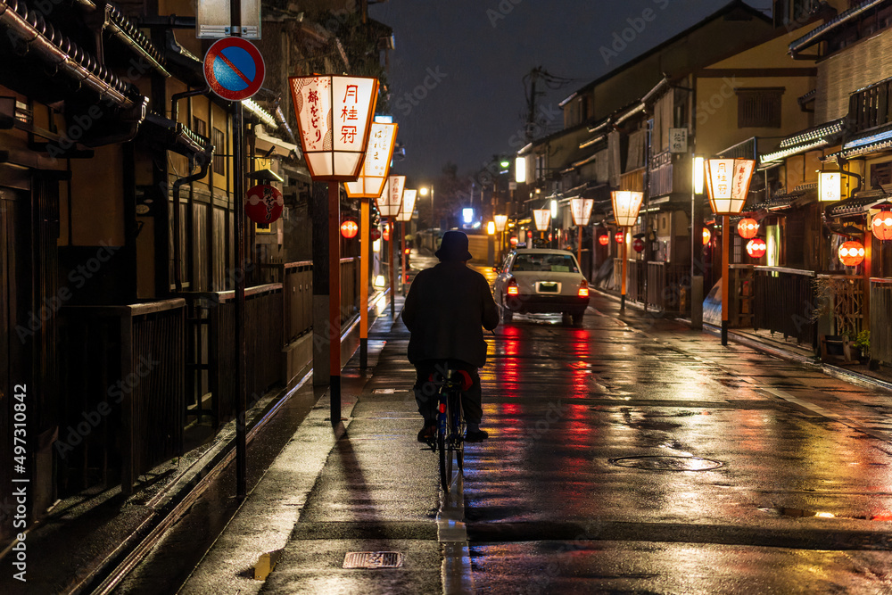 Man on a bicycle in historic Kyoto district at night