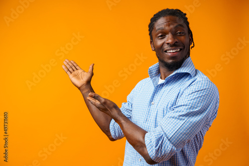 Young african american man pointing at copy space over yellow background photo