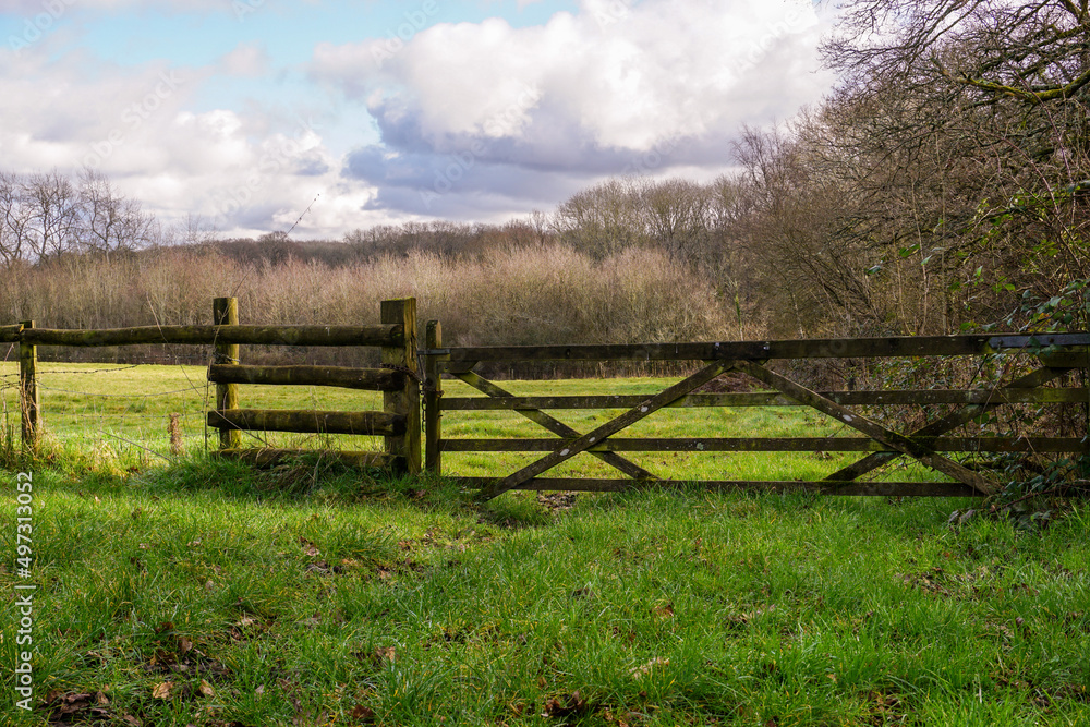 View over countryside fields in spring. Peaceful farmland  with wooden gate into field. Natural English countryside landscape 