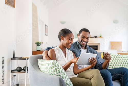 Mature black couple doing online shopping with credit card card at home