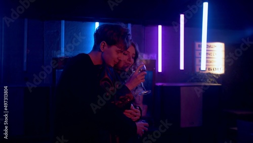 A sensual couple flirting, dancing, kissing under neon lights in a nightclub. The couple drinks alcohol, dances and kisses. Night club