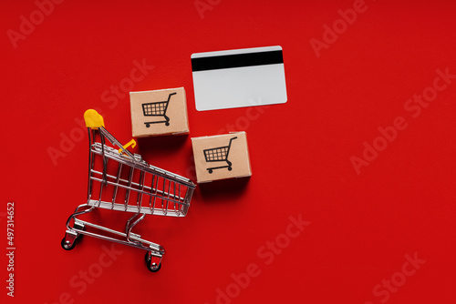 Shopping trolley, boxes and credit card. Top view. Online shopping paying by credit card