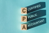 Wooden cubes building word CPA - abbreviation of certified public accountant - with shadows on light blue background.