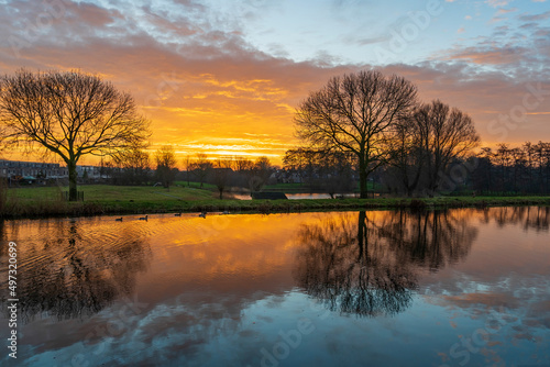 The intense colors in the sky during this sunrise on a cold winter morning are beautifully reflected in the smooth water of the canal