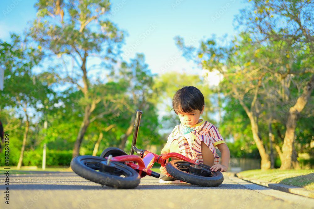 Fototapeta premium Asian boy about 2 years is riding baby balance bike and fall, learning concept