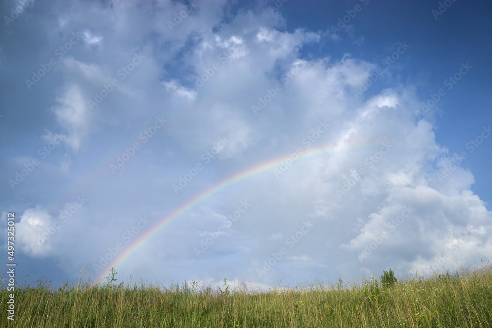 Blue cloudy sky after summer rain and colorful rainbow. Blue cloudy sky after summer rain and colorful rainbow.