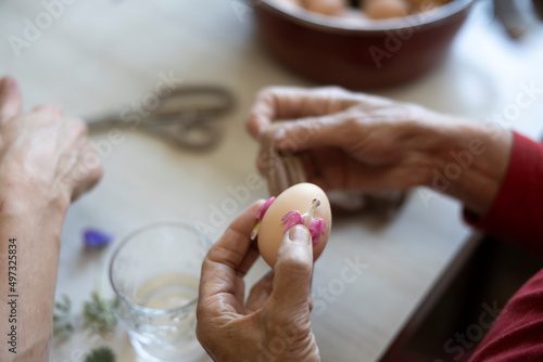 Senior Woman Putting Easter Egg with Flower Pattern on It in a Sock in Painting Process