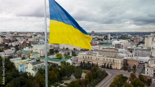 Flag of Ukraine waving close-up on epic gray cloudscape, autumn city aerial view near Svyato-Pokrovskyy Monastyr in Kharkiv downtown, Ukraine photo