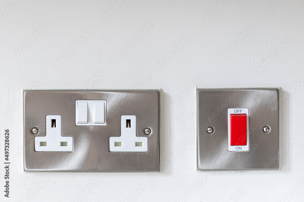 Stainless steel electric double socket and red on/off switche mounted on a white wall Stainless steel electric double socket and red on/off switche mounted on a white wall