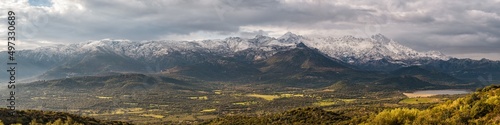 Panoramic view of the Regino valley and Lac de Codole in the Balagne region of Corsica with the snow capped peaks of Monte Padru, Monte San Parteo and Monte Grosso in the distance photo