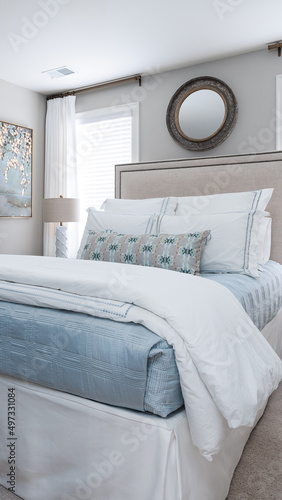 Neutral bed linens and nailhead trim headboard on this beautifully dressed white bed.