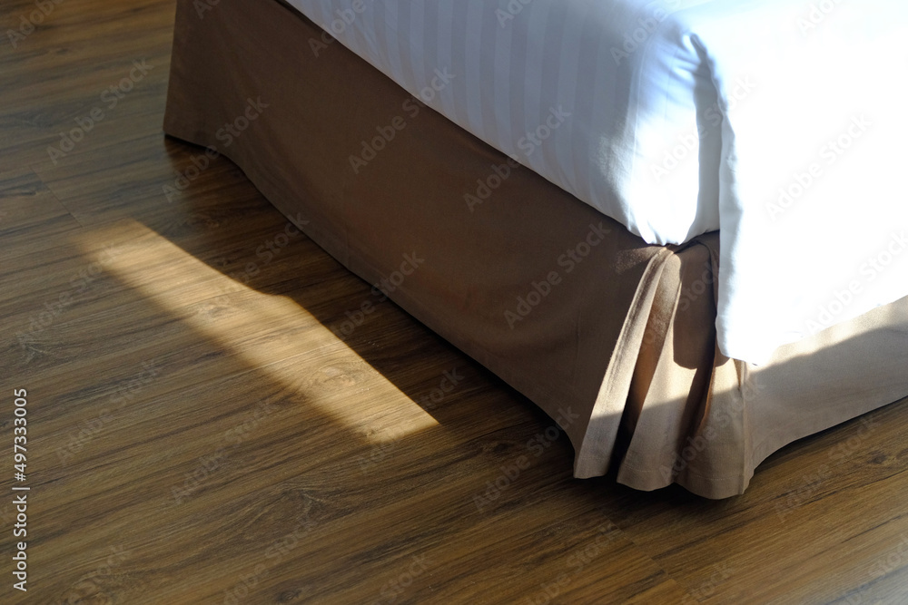 Bottom end of clean single bed on wood floor with sunlight in the morning Bottom end of clean single bed on wood floor with sunlight in the morning