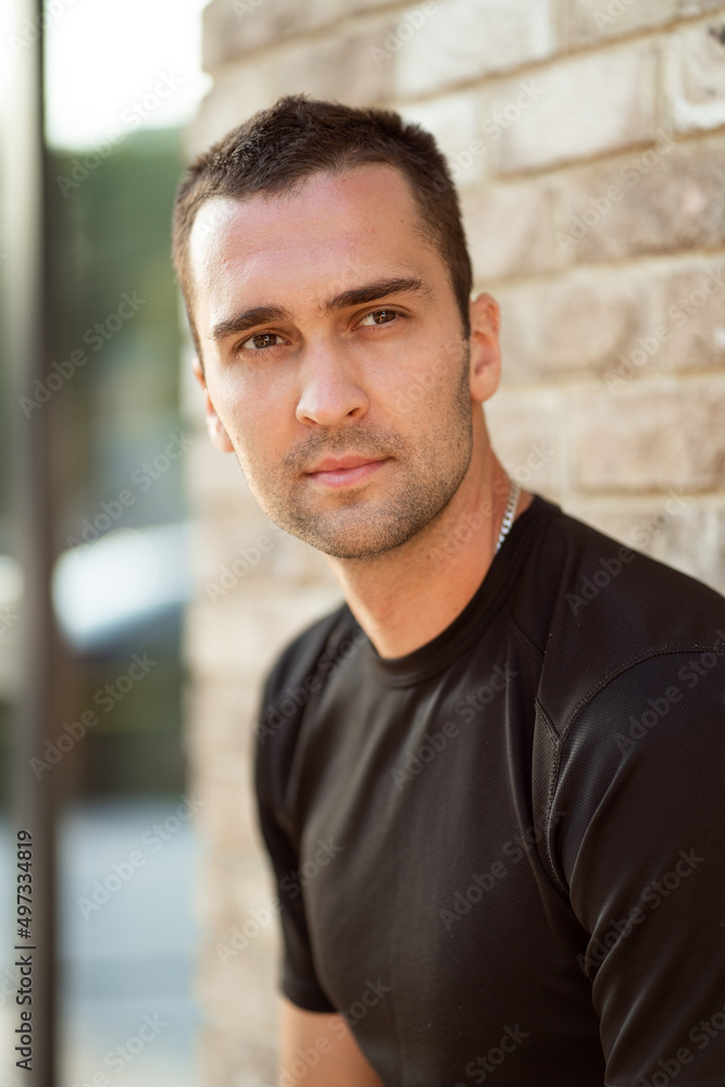 handsome man with short bristles in a black T-shirt on a background of a brick wall handsome man with short bristles in a black T-shirt on a background of a brick wall