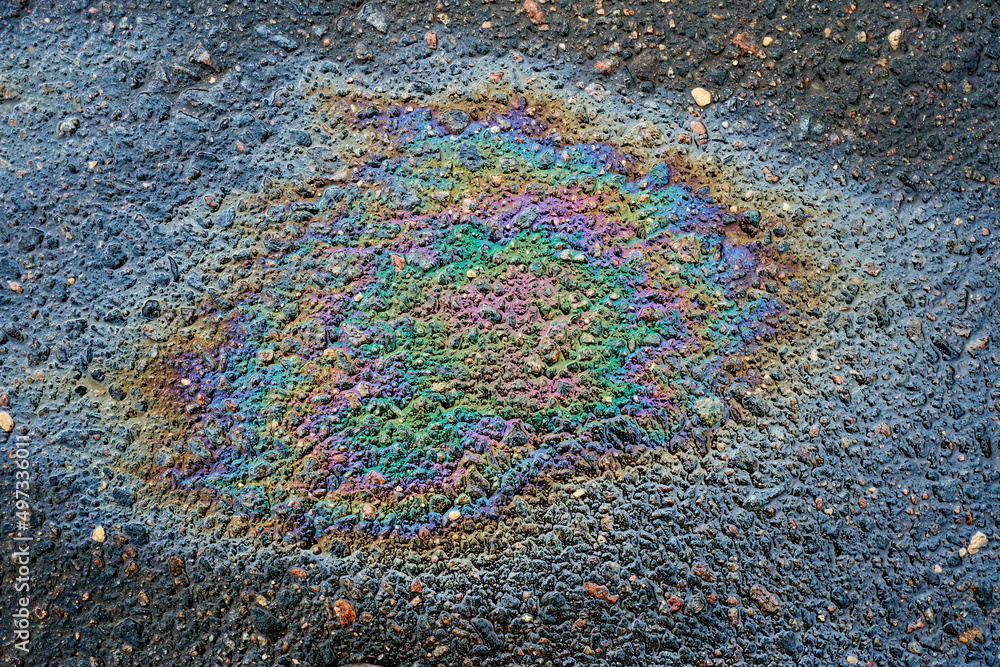 Obraz premium Rainbow gasoline oil spill on the pavement as a texture or background.