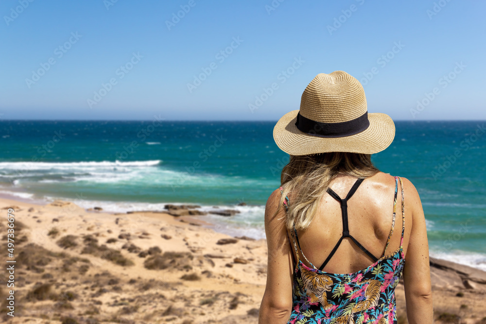 Young woman on her back with a hat looking at the sea. Copy space. Selective focus.