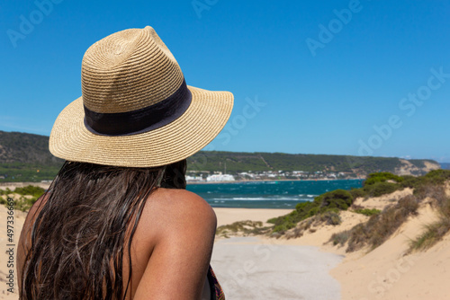 Young woman on her back with a hat looking at the sea. Copy space. Selective focus.