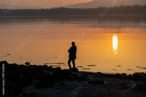 Woman silhouetted against the reflection of sunlght on the west coat of Scotland photo