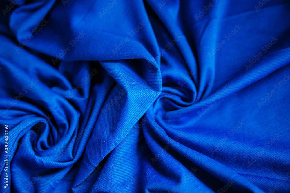 Blue wrinkled draped fabric. Sewing material is on the table. Blue wrinkled draped fabric. Sewing material is on the table.