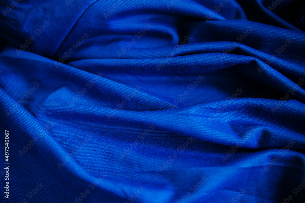 Obraz premium Blue wrinkled draped fabric. Sewing material is on the table.