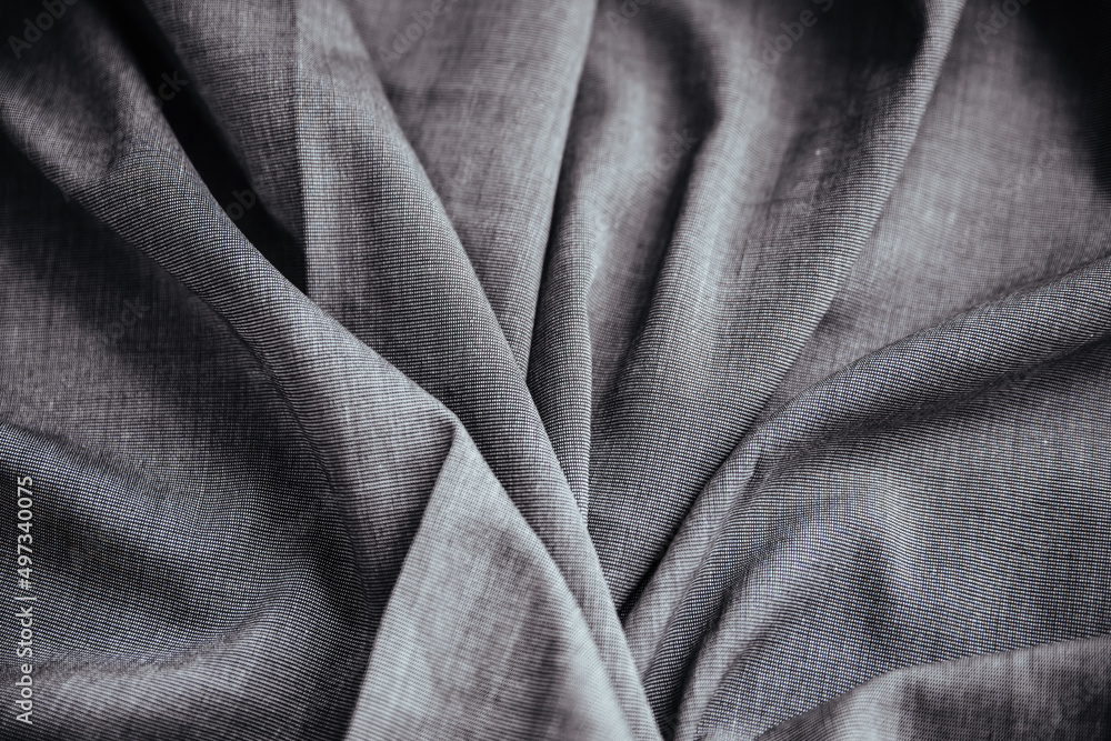 Obraz premium Gray wrinkled draped fabric. Sewing material is on the table.