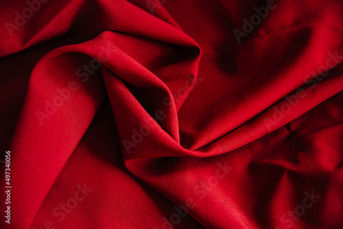 Red wrinkled fabric drapery. Sewing material is on the table.