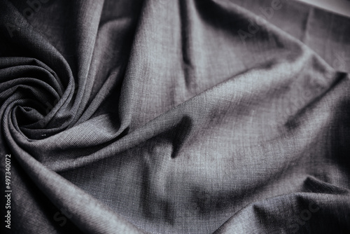 Gray wrinkled draped fabric. Sewing material is on the table.