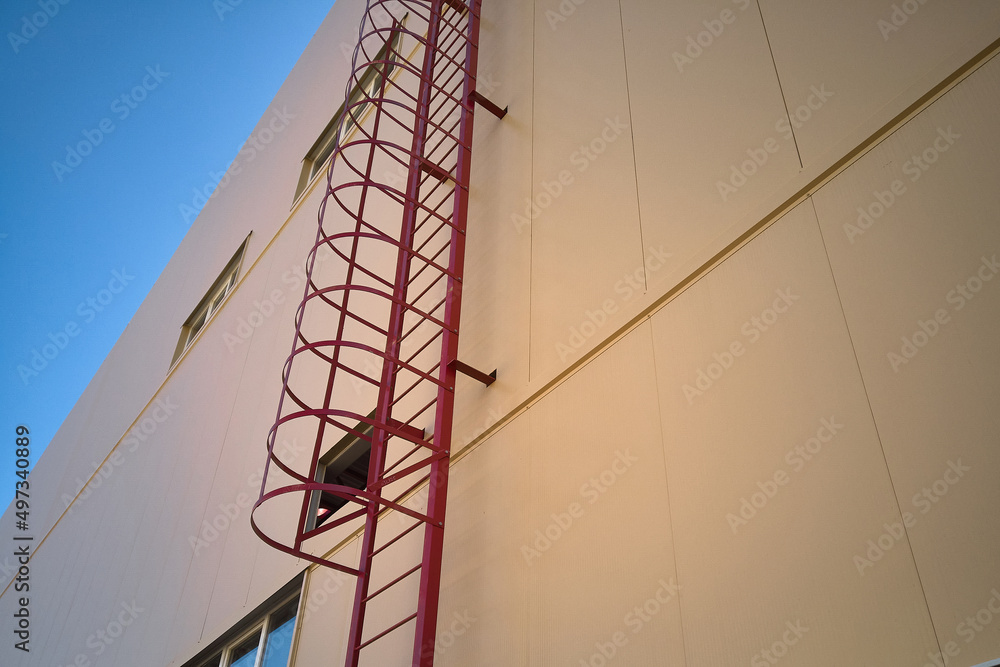 Outdoor fire escape ladder on industrial building wall. Bottom up view