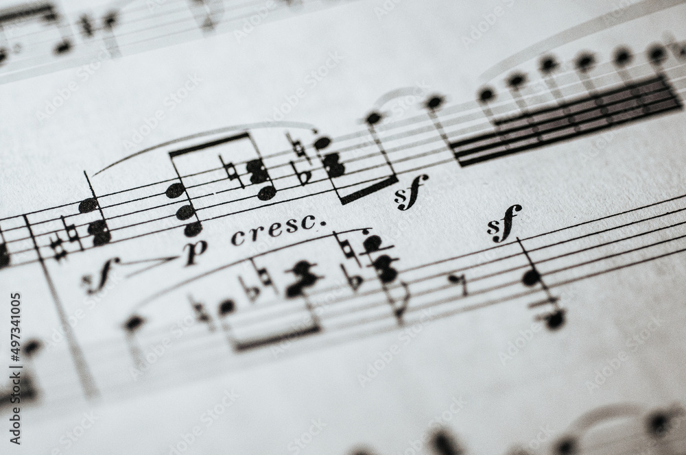 Macro photo of complicated sheet music in bass and treble clef for piano with Italian notation Macro photo of complicated sheet music in bass and treble clef for piano with Italian notation