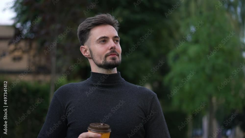 Smiling handsome man drinking morning coffee walking on sunny city street leaving. Portrait of happy positve Caucasian young guy strolling outdoors in town. Lifestyle and happiness Smiling handsome man drinking morning coffee walking on sunny city street leaving. Portrait of happy positve Caucasian young guy strolling outdoors in town. Lifestyle and happiness