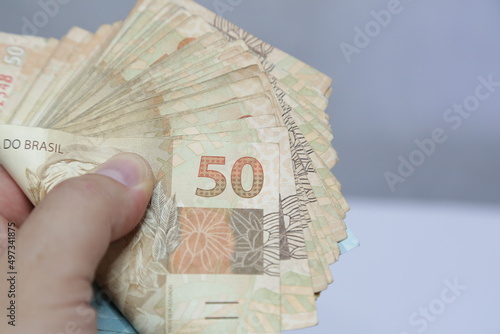 Nota de 50 reais brasileiro com celular na mão. photo