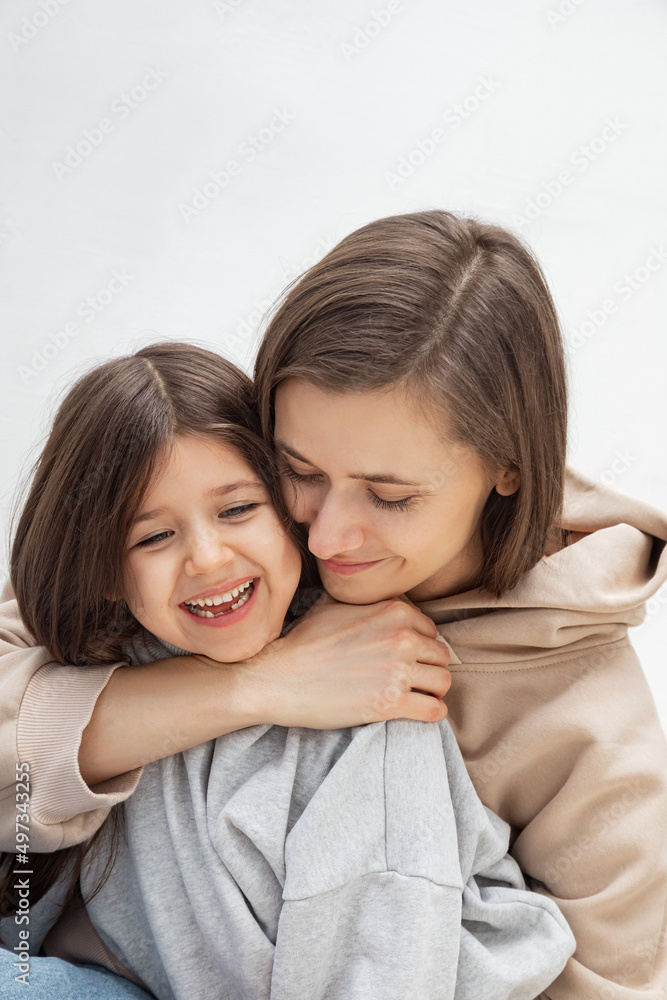Mother woman in casual clothes hugging a cute baby girl. Mother, little daughter isolated on pastel wall background, studio portrait, mother's day, love, family, fatherhood, childhood, childhood