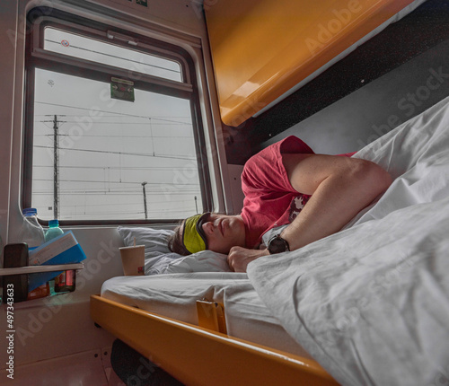 Slika na platnu Blue and yellow interior of sleeping coach with sleeping man