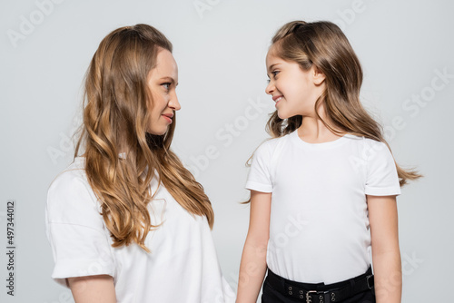 cheerful girl looking at mother isolated on grey.