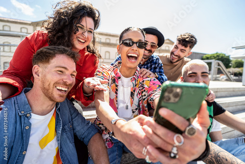 Εκτύπωση καμβά Group of happy multiracial friends using smartphone outdoors, watching social media and laughing