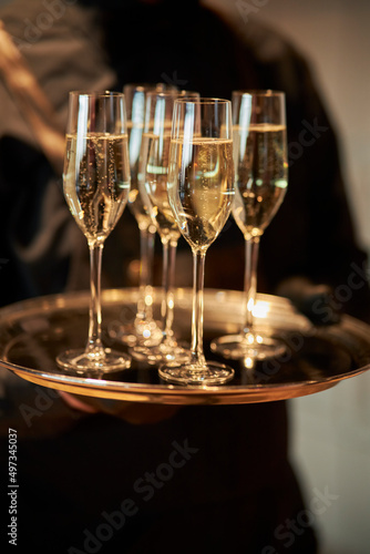 Waitress holding tray with glasses of champagne at part. closeup of a waiter with a tray and glasses of champagne. wedding reception.