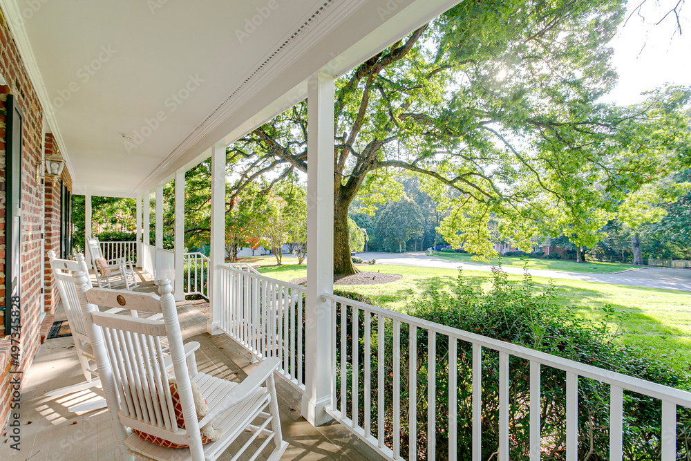 Southern country living covered front porch summer spring day tree sunlight warm sunshine white rocking chairs