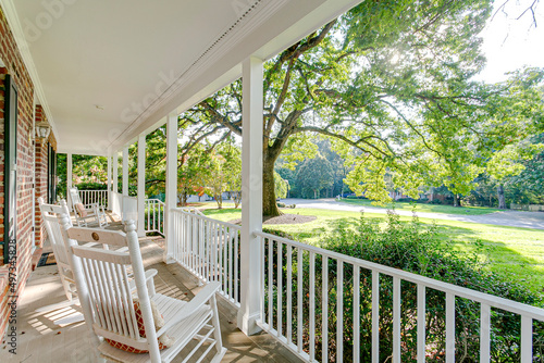 Obraz na płótnie Southern country living covered front porch summer spring day tree sunlight warm sunshine white rocking chairs w salonie