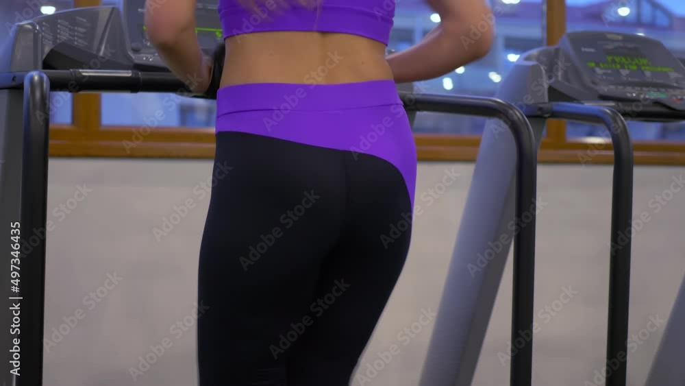 Rear view of woman in sportwears using a treadmill at gym Rear view of woman in sportwears using a treadmill at gym