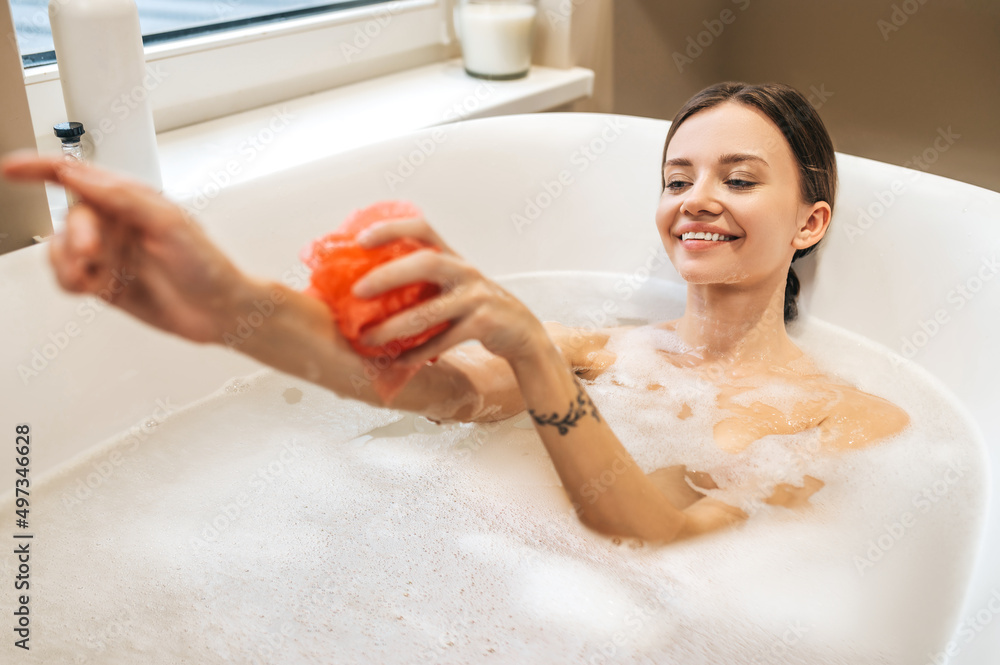 Naklejka premium Cheerful lady washing herself with a nylon loofah