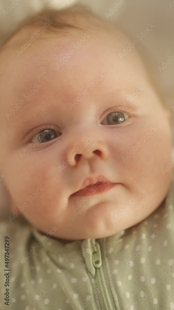 Vertical Format Portrait Video of Cute Newborn Baby Lying on the Back in Child Crib. Playful Portrait of a Caucasian Neonate Toddler at Cozy Home Space. Concept of Childhood, New Llife and Parenthood. Vertical Format Portrait Video of Cute Newborn Baby Lying on the Back in Child Crib. Playful Portrait of a Caucasian Neonate Toddler at Cozy Home Space. Concept of Childhood, New Llife and Parenthood.