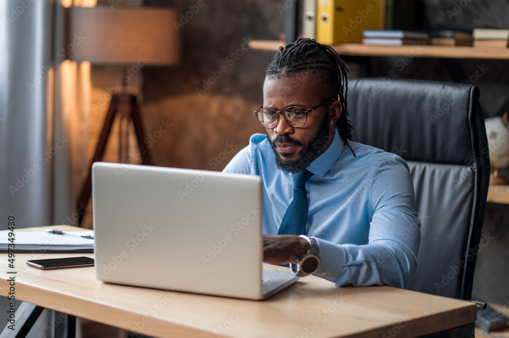 Concentrated businessman in eyeglasses using his laptop Concentrated businessman in eyeglasses using his laptop