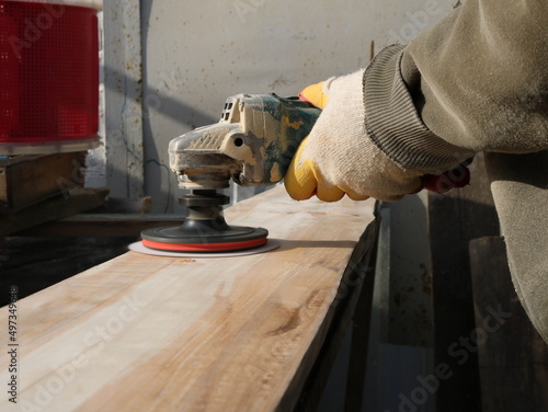 Fotografie processing a grinder with an emery nozzle of a board in a carpenter's workshop,