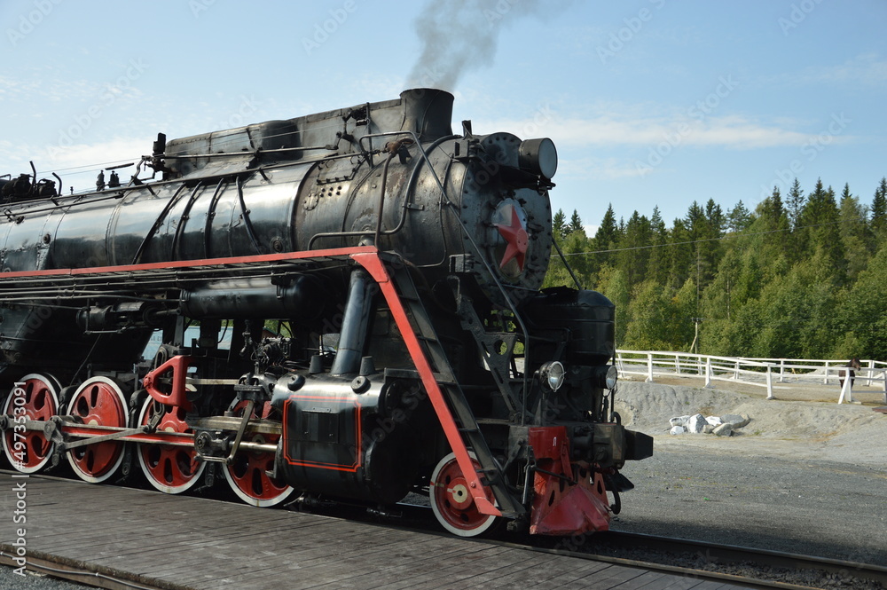 Fototapeta premium retro train in karelia, russia. steam train on move in forest. old authentic train on go, summer. black and red train