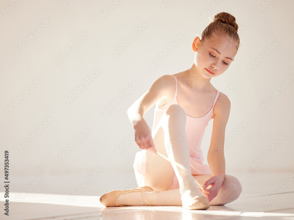 Treat each class as if it were your first. Shot of a young ballerina tying her ballet slipper in a dance studio.
