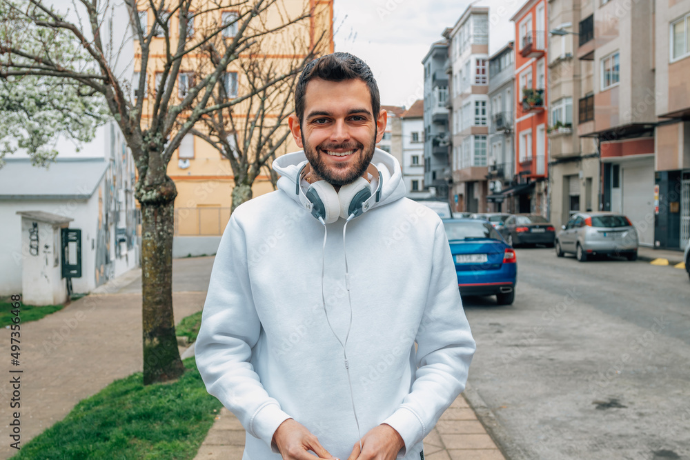 urban style young man walking in the street with headphones