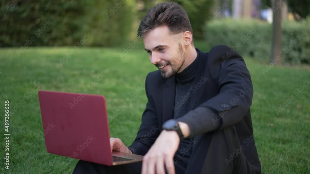 Handsome positive intelligent man laughing surfing social media on laptop sitting in spring summer park. Happy handsome Caucasian businessman messaging online outdoors on break Handsome positive intelligent man laughing surfing social media on laptop sitting in spring summer park. Happy handsome Caucasian businessman messaging online outdoors on break