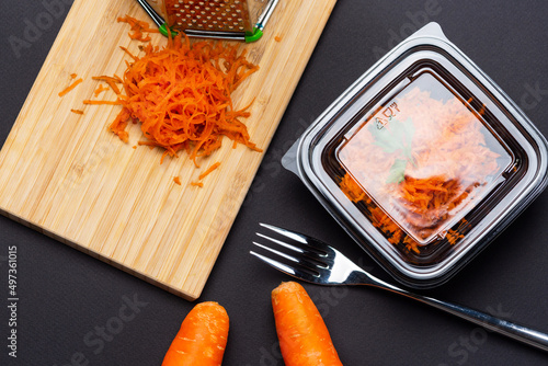 Shredding carrots with lunch box package on black table background