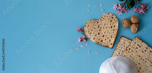 blue big banner Layout of Matzah in shape of heart decorate by pink flowers, kipa and Walnut. Traditional of Jewish Holiday on Passover symbol of lovely family. top view. love and care. space for text photo